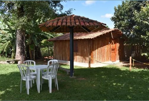 Chalé do Lago, cabana rústica de madeira com mesa e cadeiras brancas no jardim