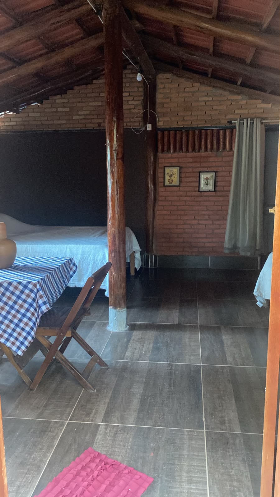 Espaço interno do Chalé do Lago, com mesa, cadeiras e cama em estrutura rústica de madeira