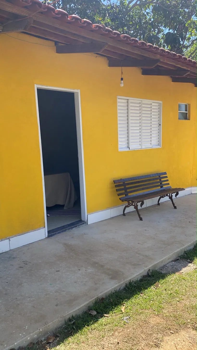 Chalé Pirarara, pintado em amarelo dourado, com varanda e banco de madeira