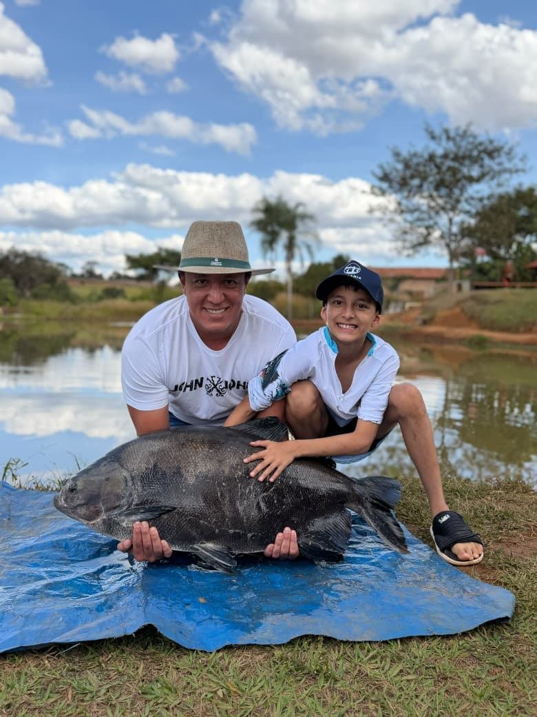 Pai e filho celebrando a pesca esportiva no lago do Recanto